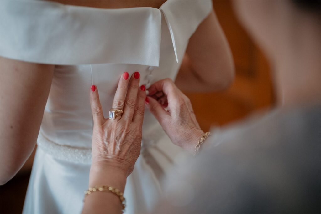 Dettaglio dell'abito da sposa mentre viene allacciato