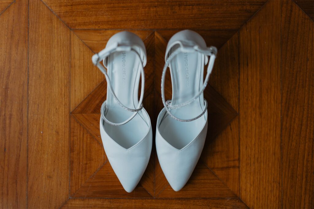 Le scarpe bianche della sposa su un pavimento in legno
