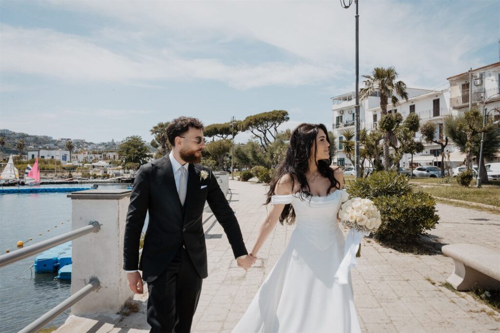 Gli sposi mano nella mano sul lungomare