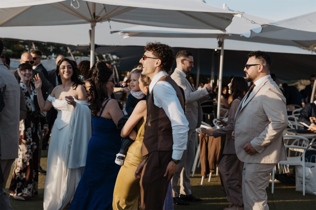 Gli sposi ballano con gli invitati al tramonto