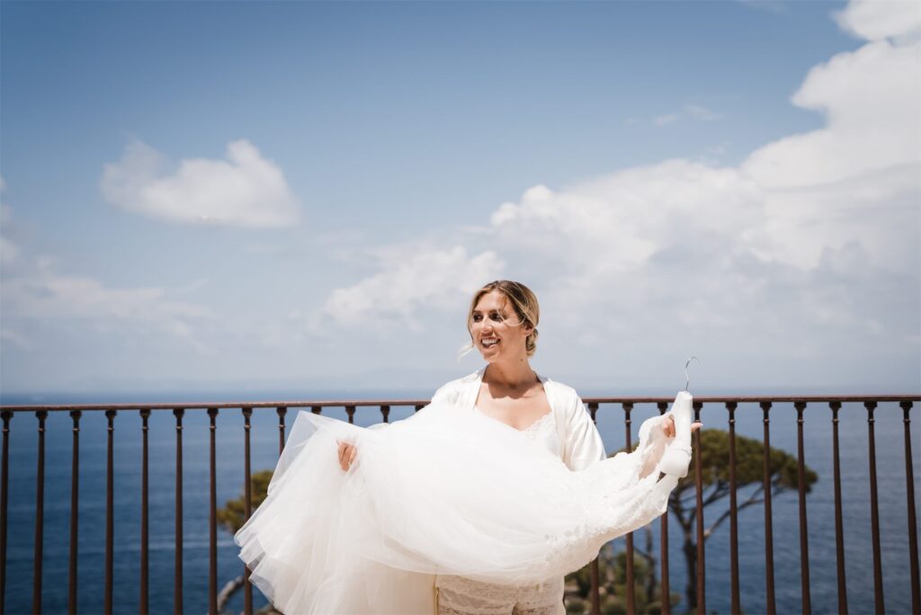 Beatrice solleva l'abito sulla terrazza sul mare