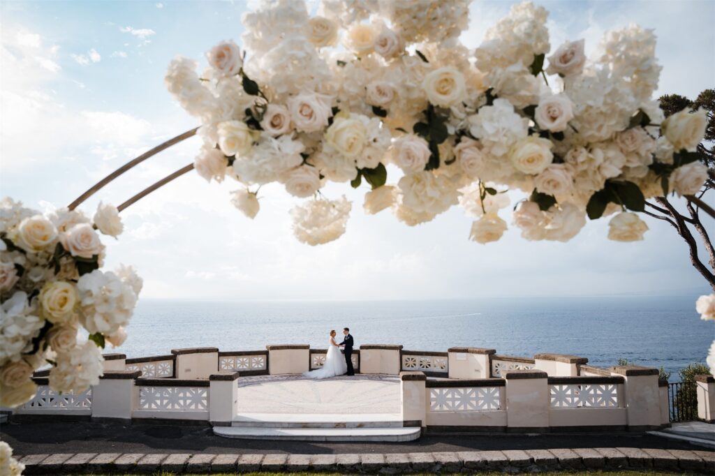 Gli sposi con l'arco di fiori sulla terrazza sul mare