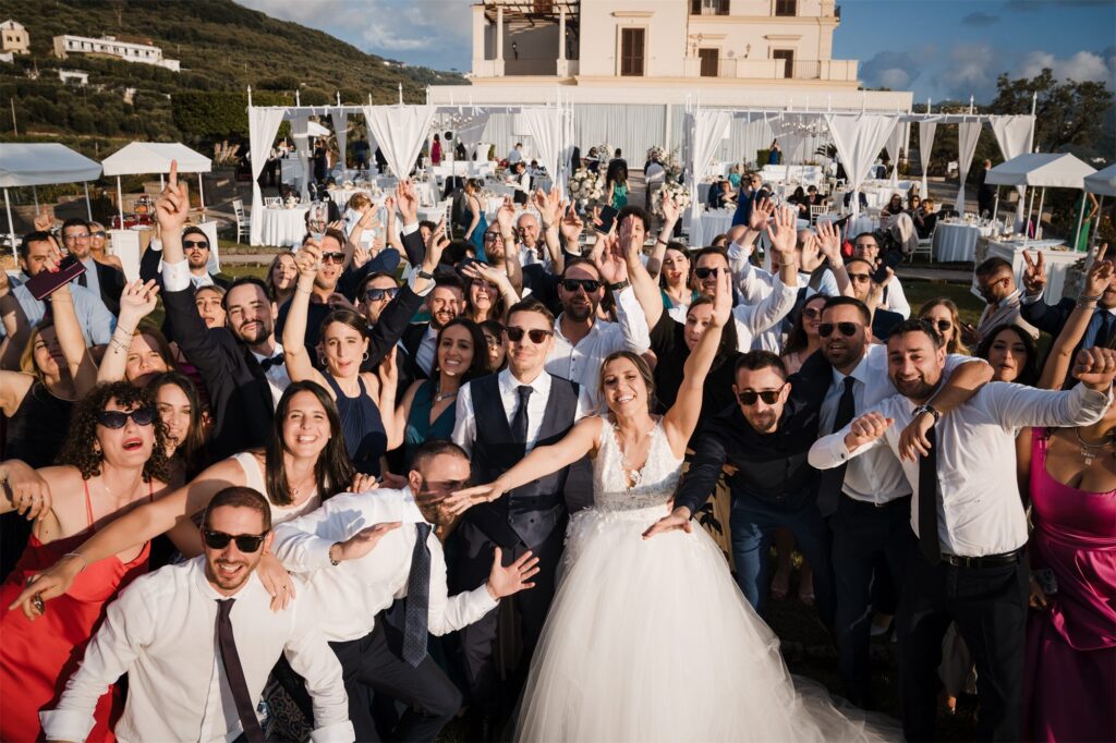 Tutti gli invitati con le braccia in alto alla festa di Villa Angelina
