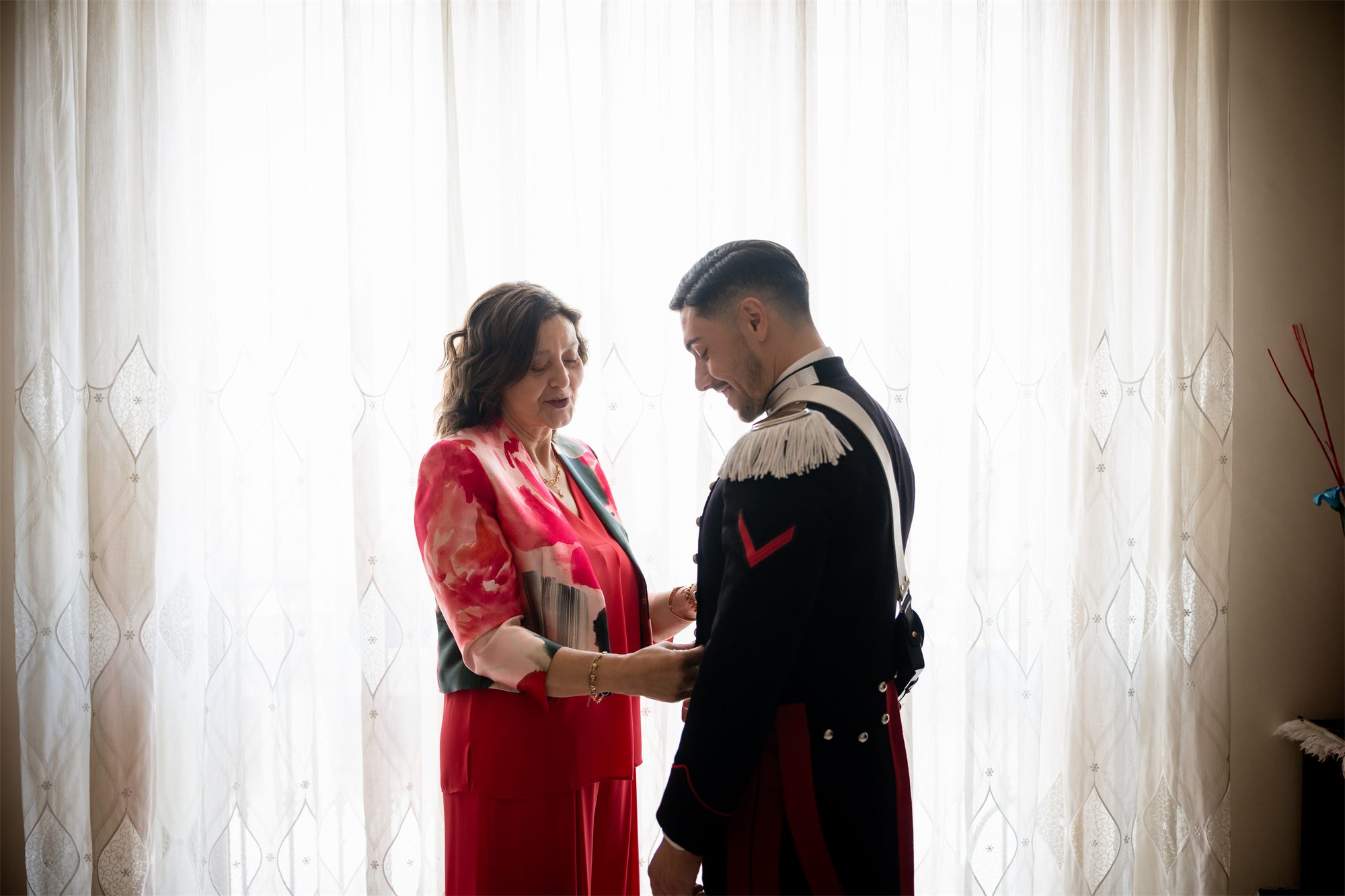 La mamma sistema la spallina dell'uniforme allo sposo durante la vestizione