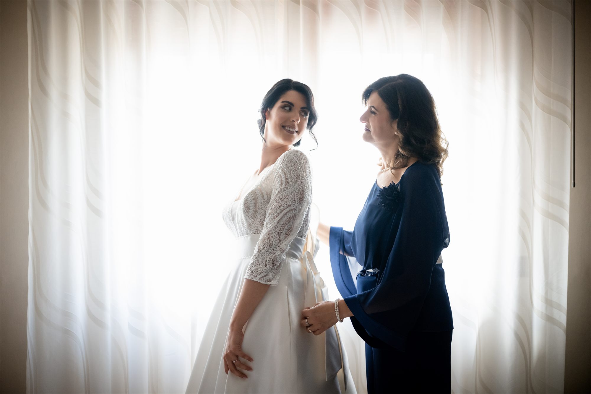 La sposa e la mamma in controluce davanti alla finestra