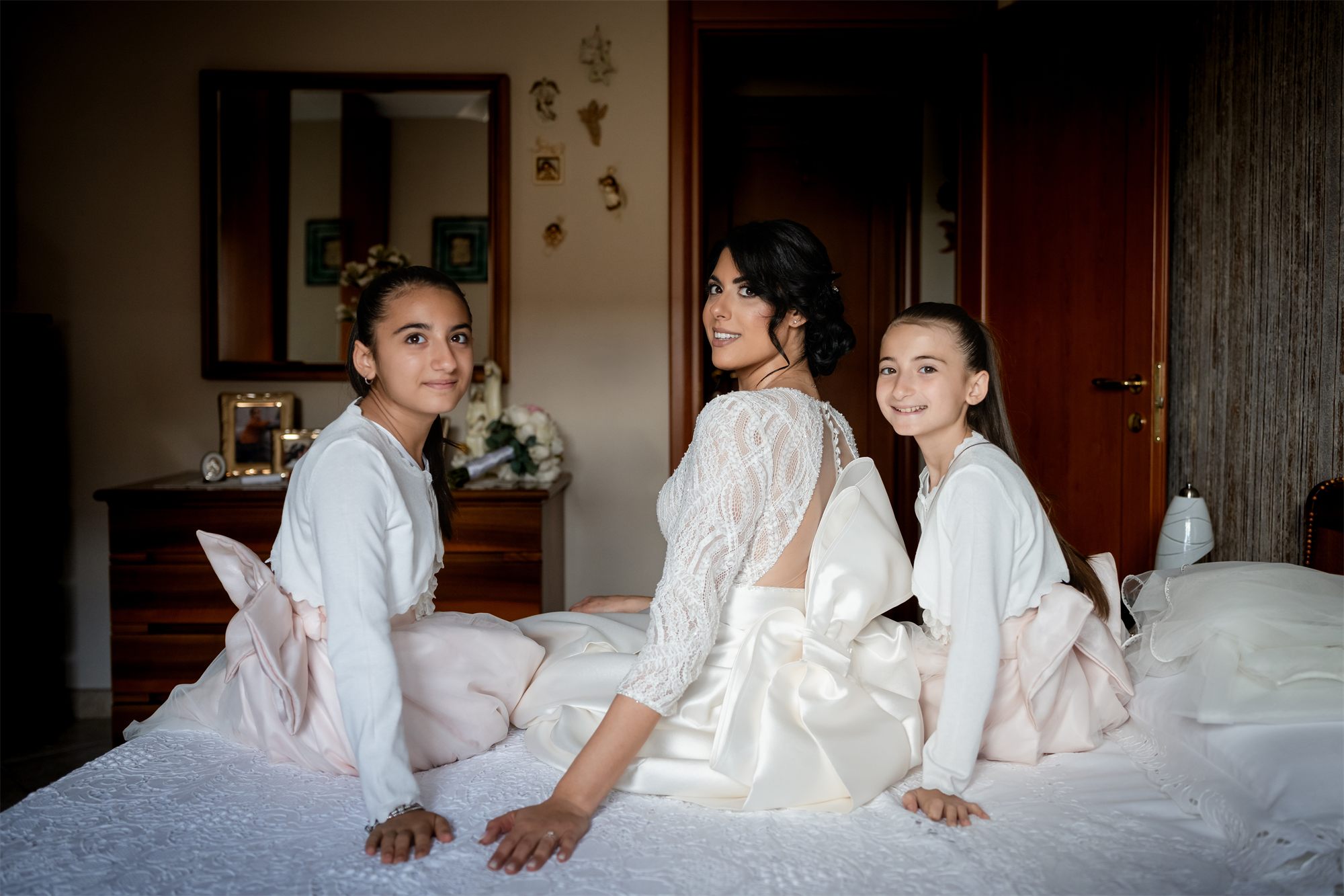 La sposa con le damigelle sedute sul letto, ridono insieme