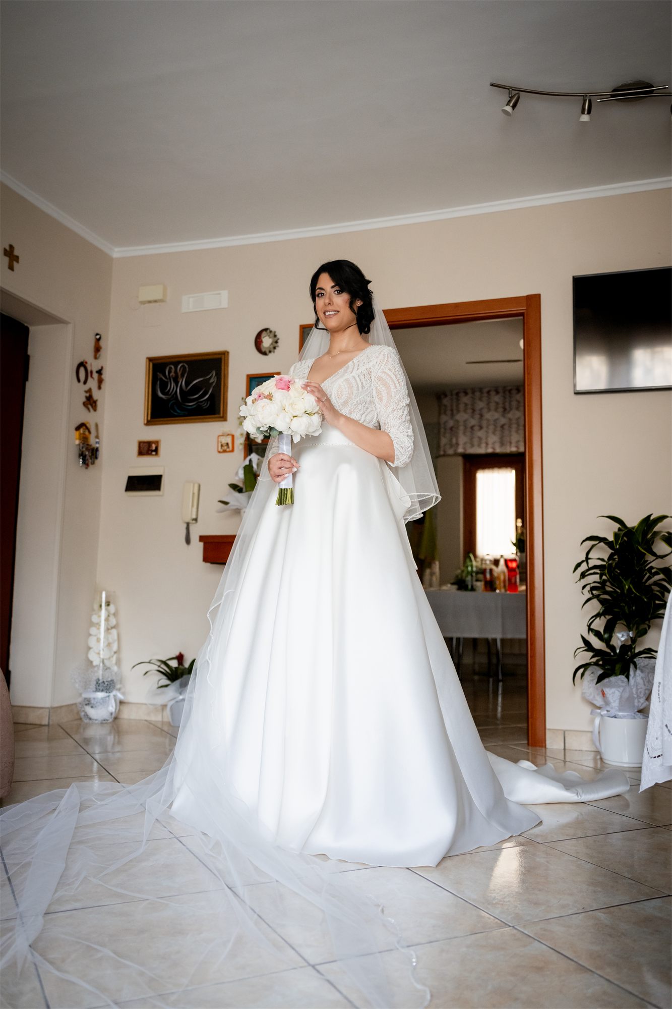 La sposa con il velo nel salone di casa, pronta per uscire