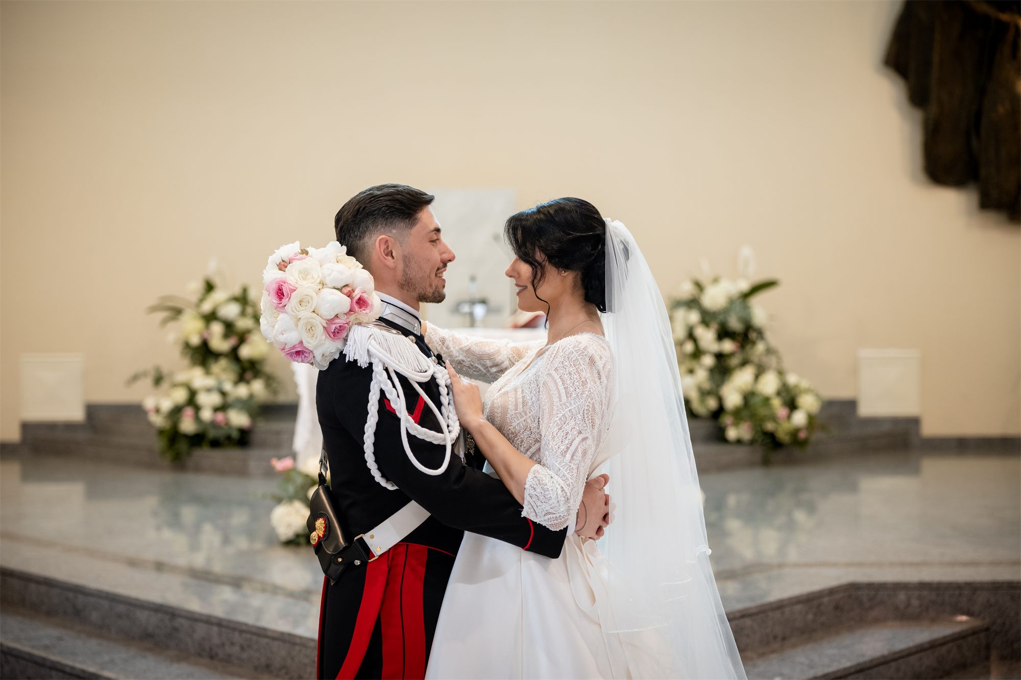 Il bacio degli sposi davanti ai fiori dell'altare
