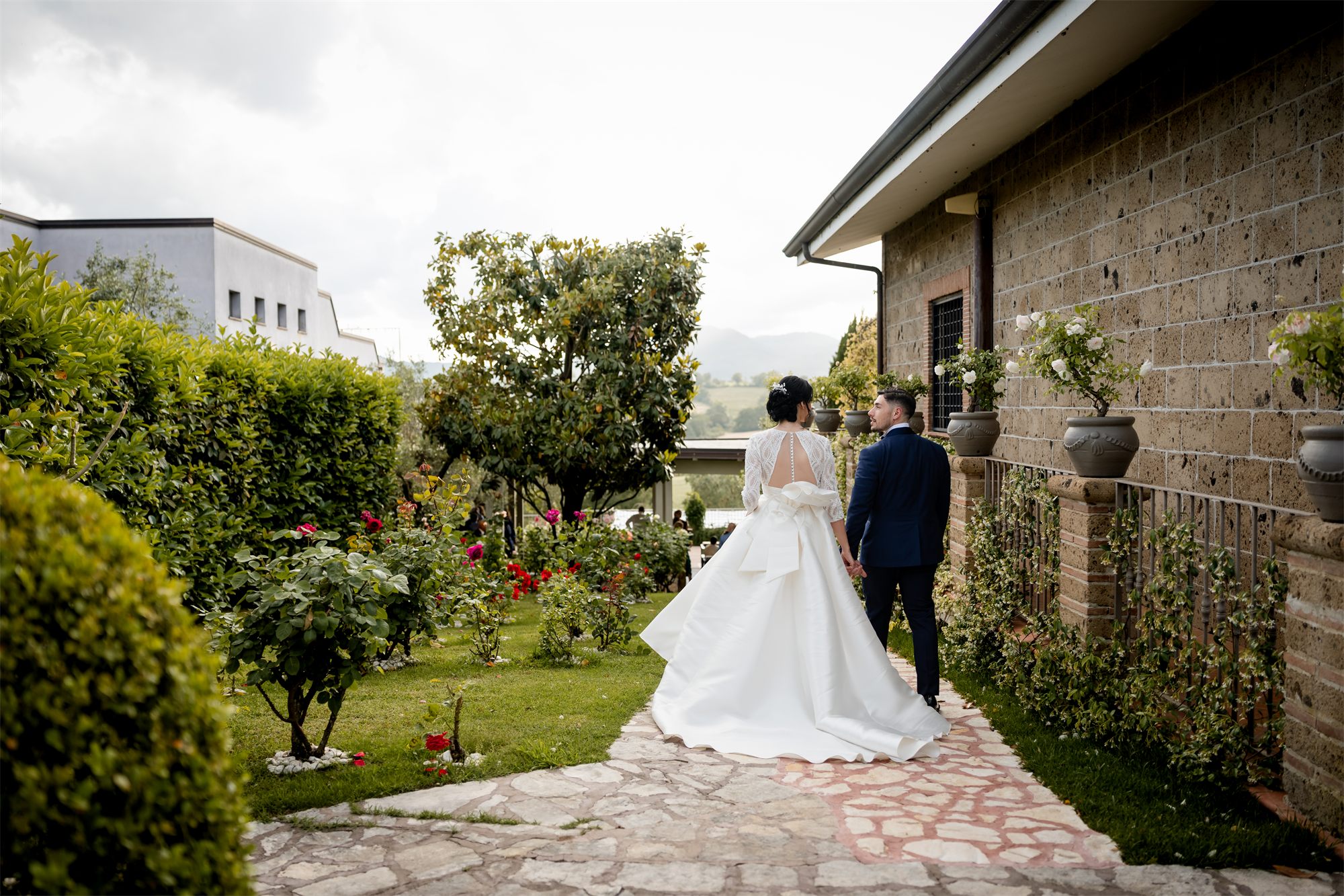 La sposa lungo il vialetto del giardino di Colle Rajano, tra rose e cespugli