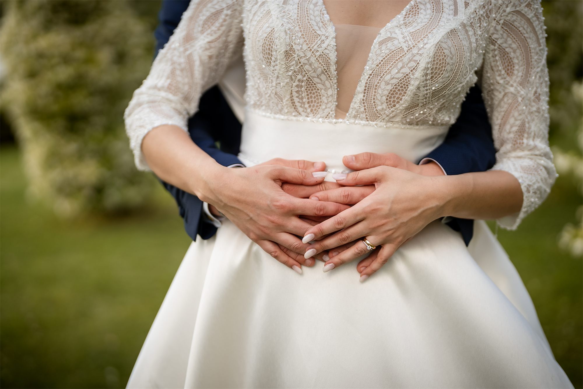 Le mani dello sposo sull'abito della sposa, nel giardino di Colle Rajano