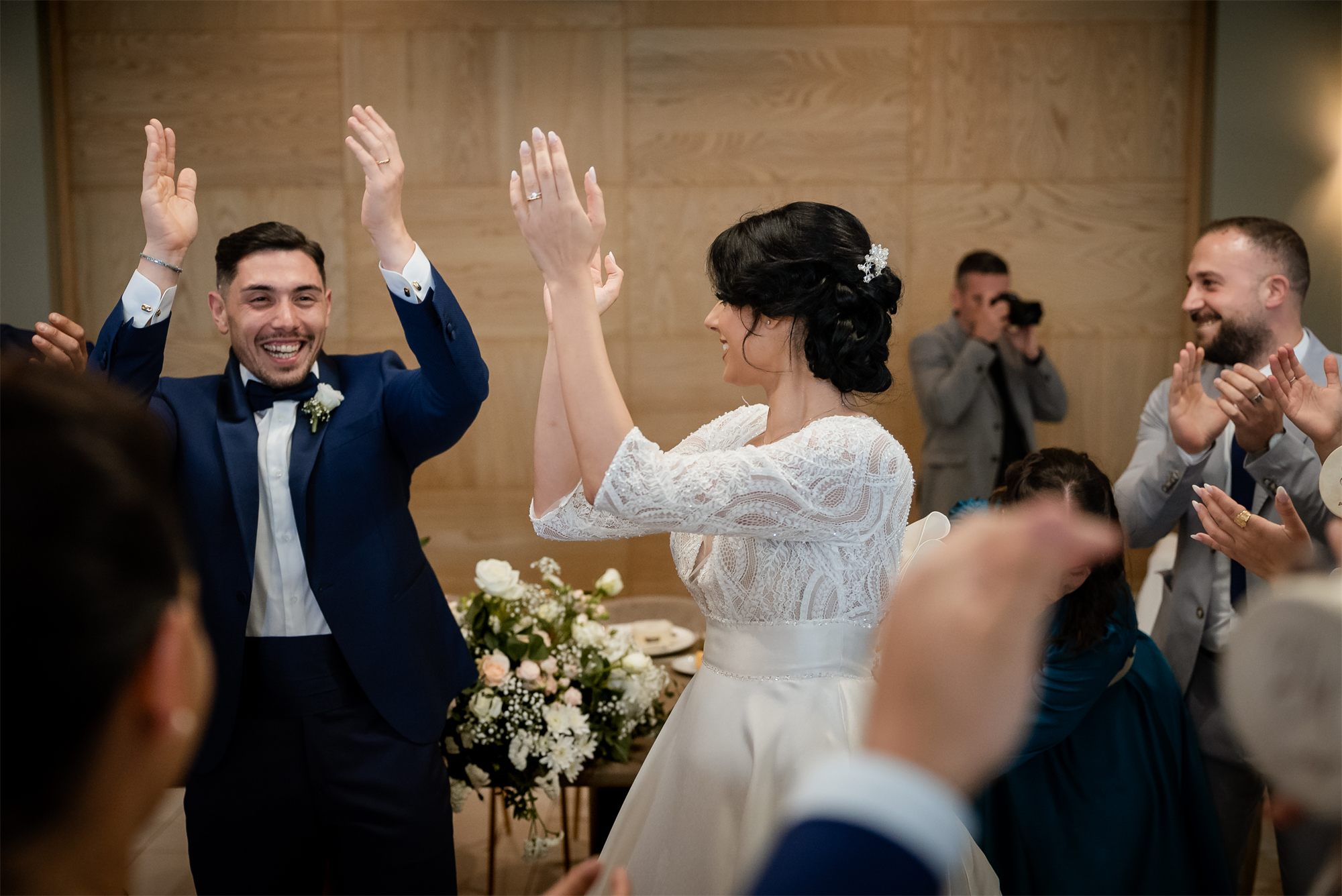 Gli sposi festeggiano con le braccia al cielo tra gli invitati