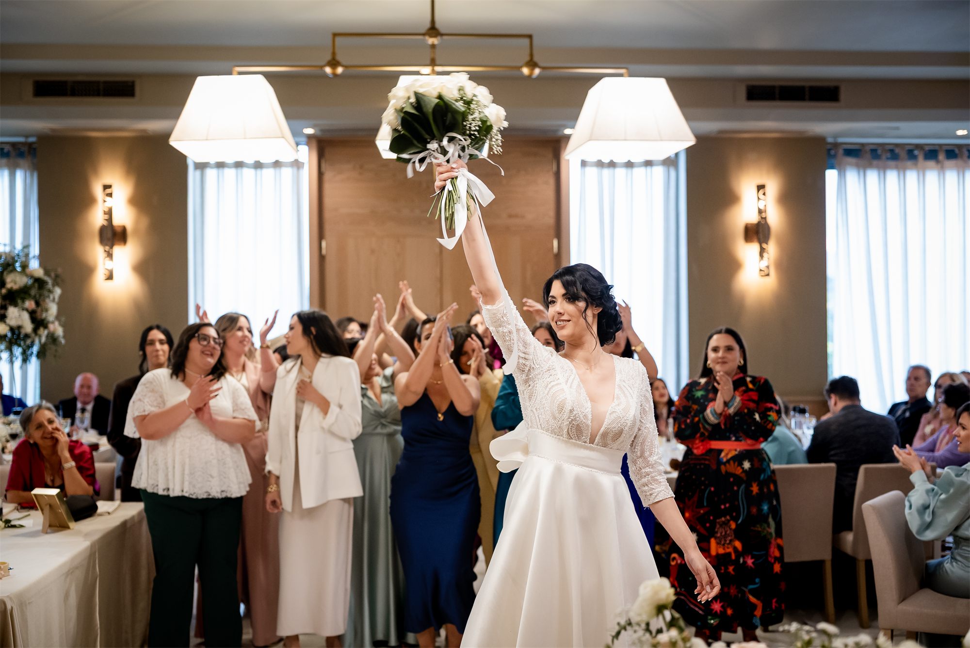 La sposa con il bouquet in alto tra le invitate