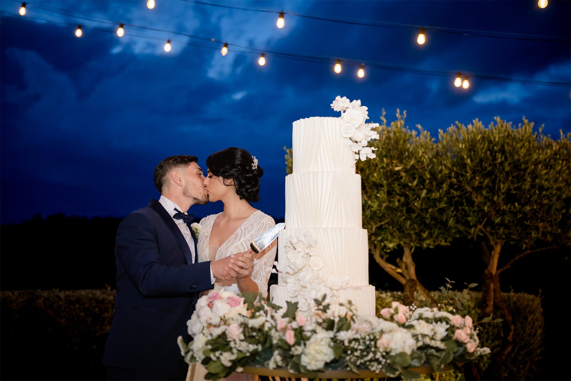 Il bacio degli sposi davanti alla torta nuziale a Colle Rajano