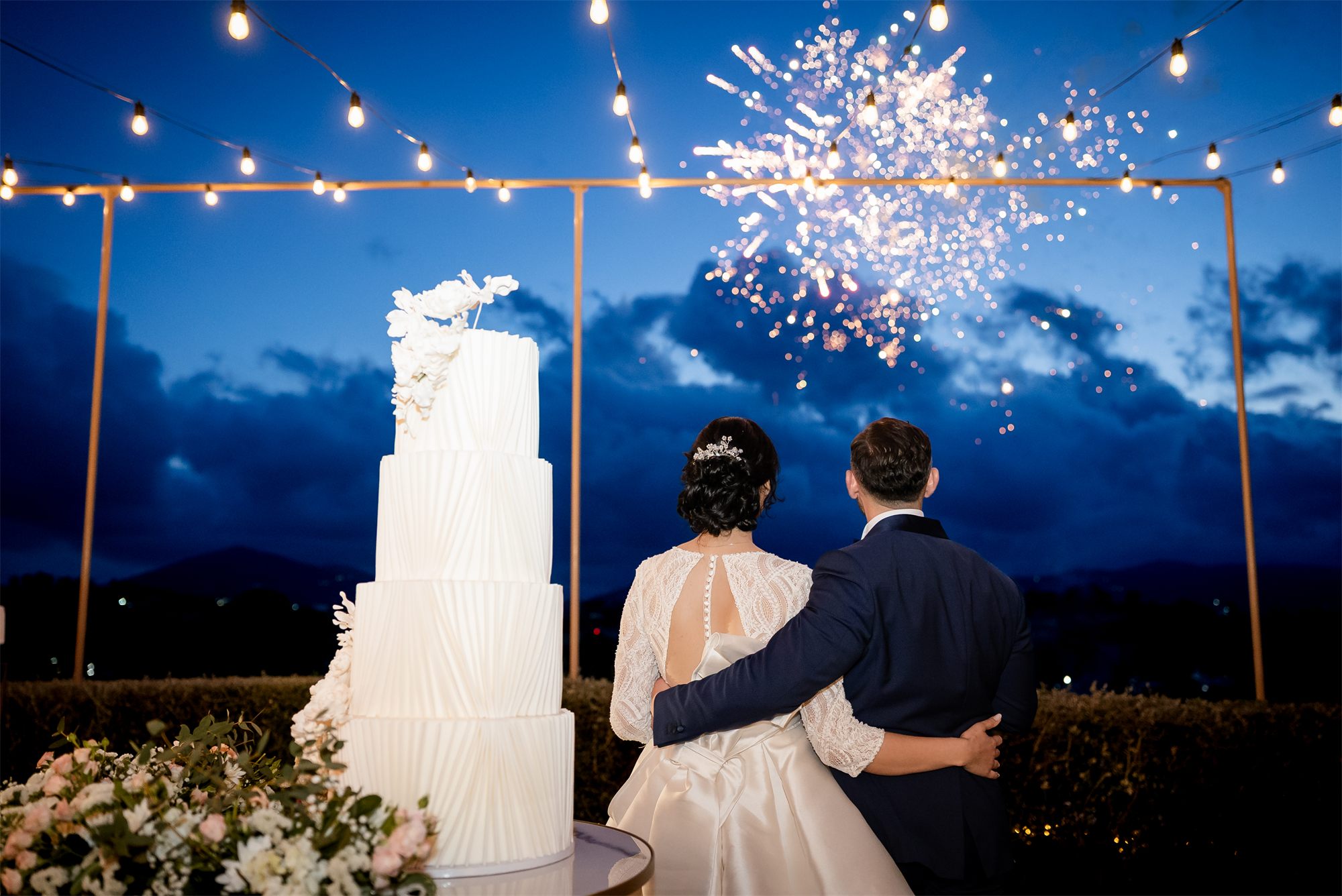 I fuochi d'artificio dietro la torta nuziale e gli sposi abbracciati