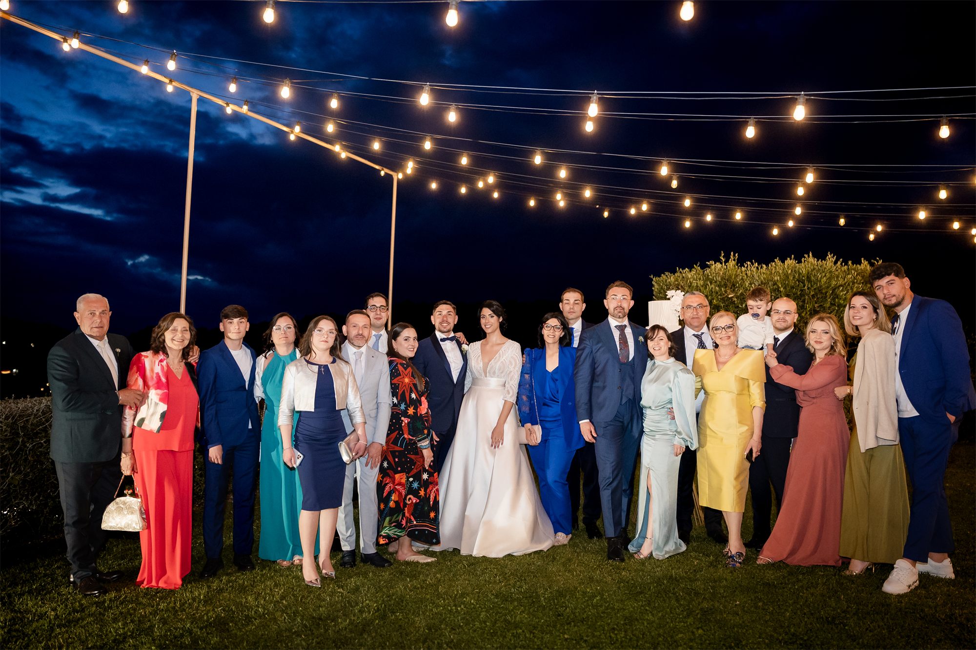 Gli sposi con tutti gli invitati nel giardino illuminato di Colle Rajano