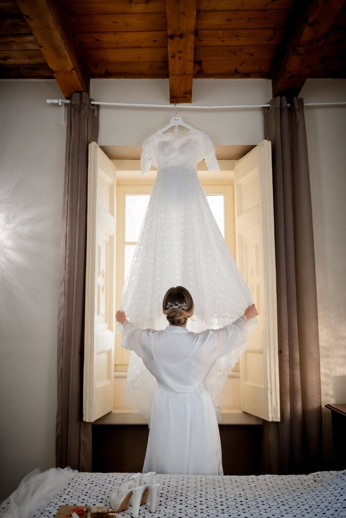 L'abito da sposa appeso alla finestra, con la sposa in vestaglia