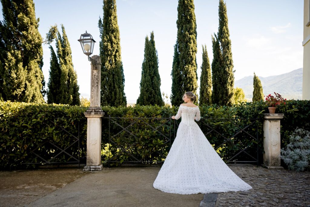 La sposa di spalle tra i cipressi del giardino