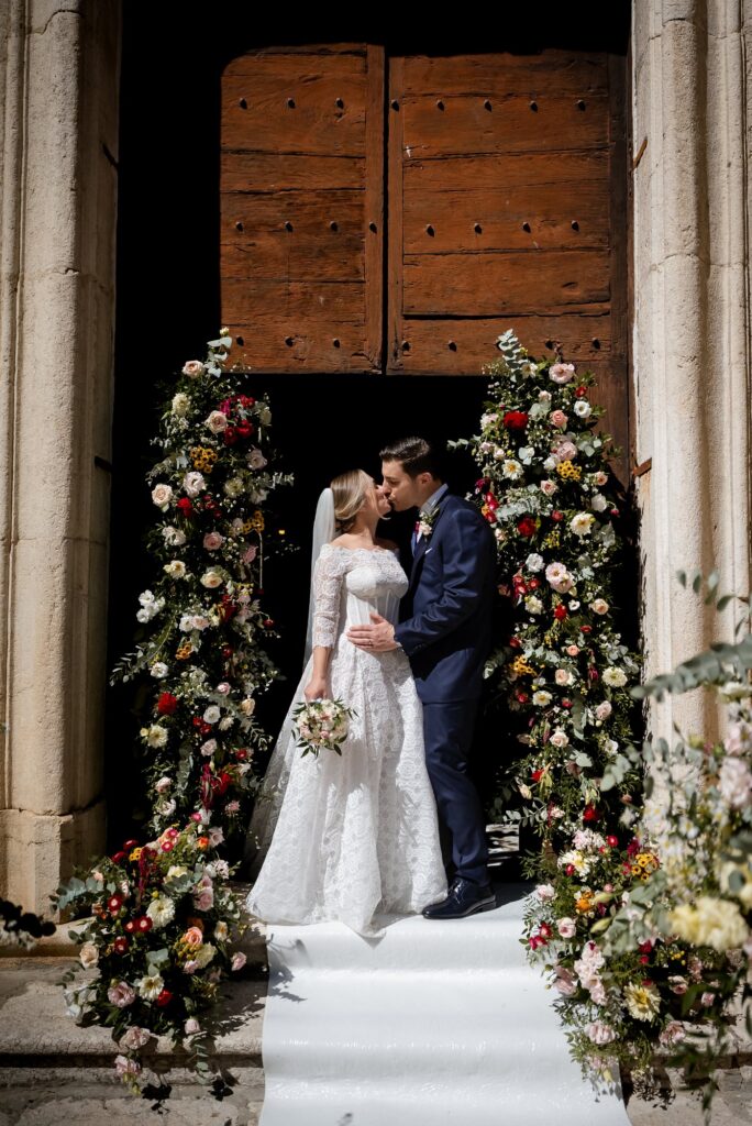 Il bacio sotto l'arco di fiori all'uscita dalla chiesa