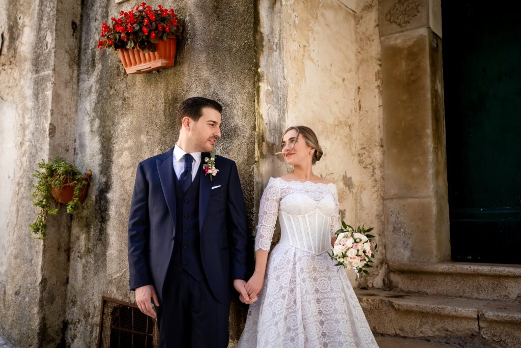 Gli sposi mano nella mano davanti a un muro antico