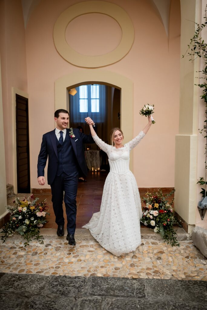 La sposa alza le braccia entrando nel cortile
