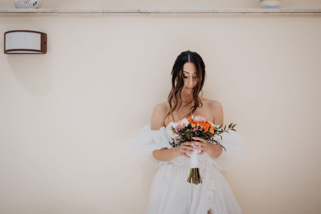 Tonia con il bouquet arancio e pesca contro il muro bianco