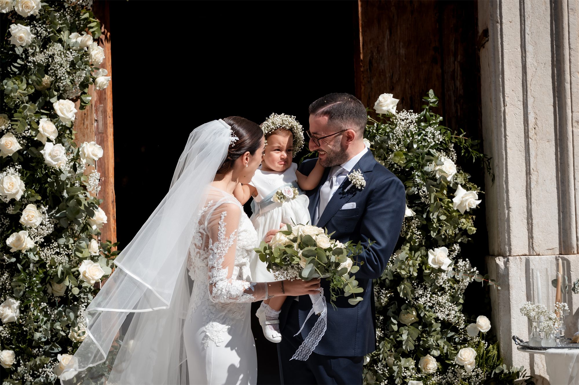 Marcello e Teresa con la bambina tra i fiori all'ingresso della chiesa