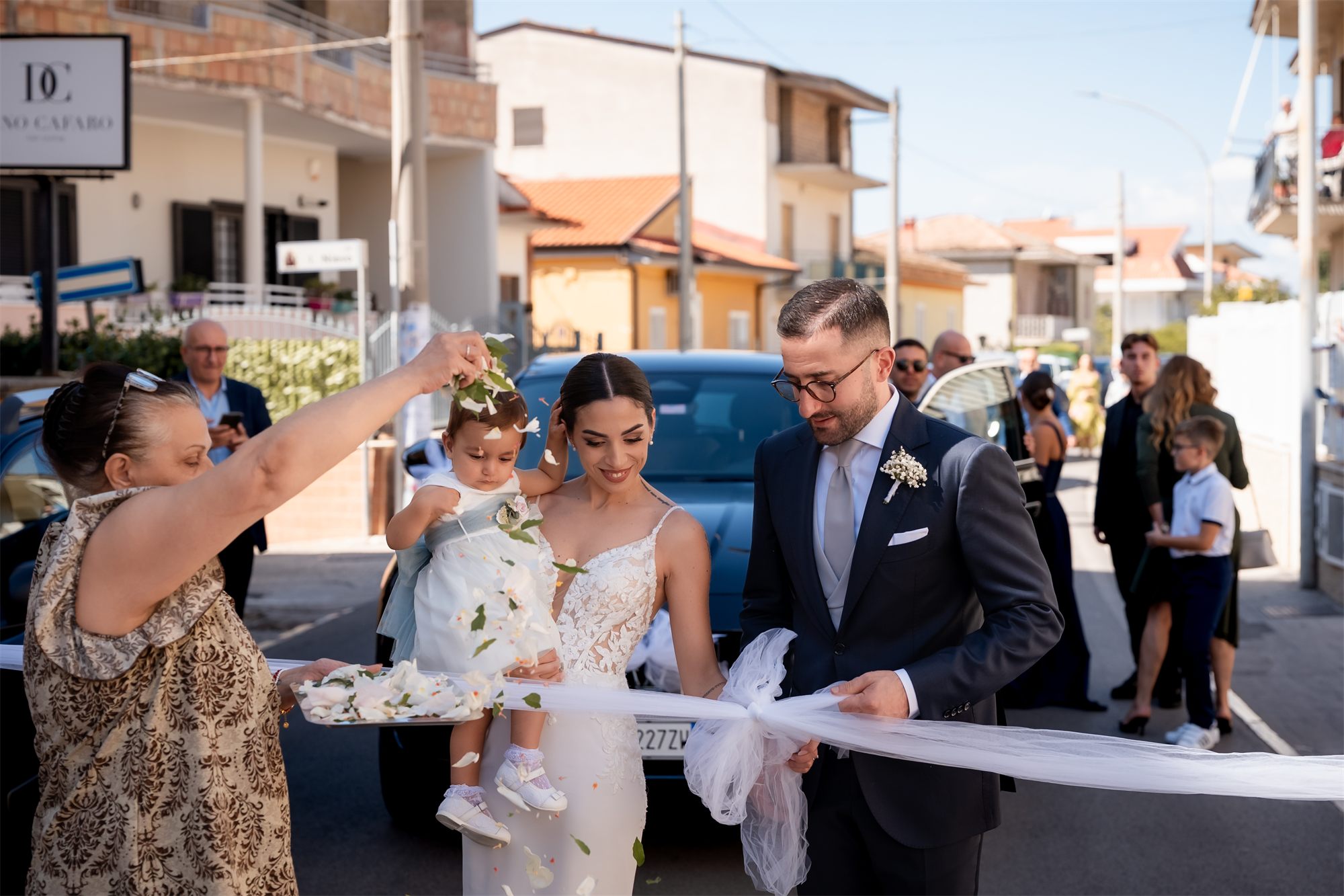 Gli sposi e la bambina al nastro con gli invitati