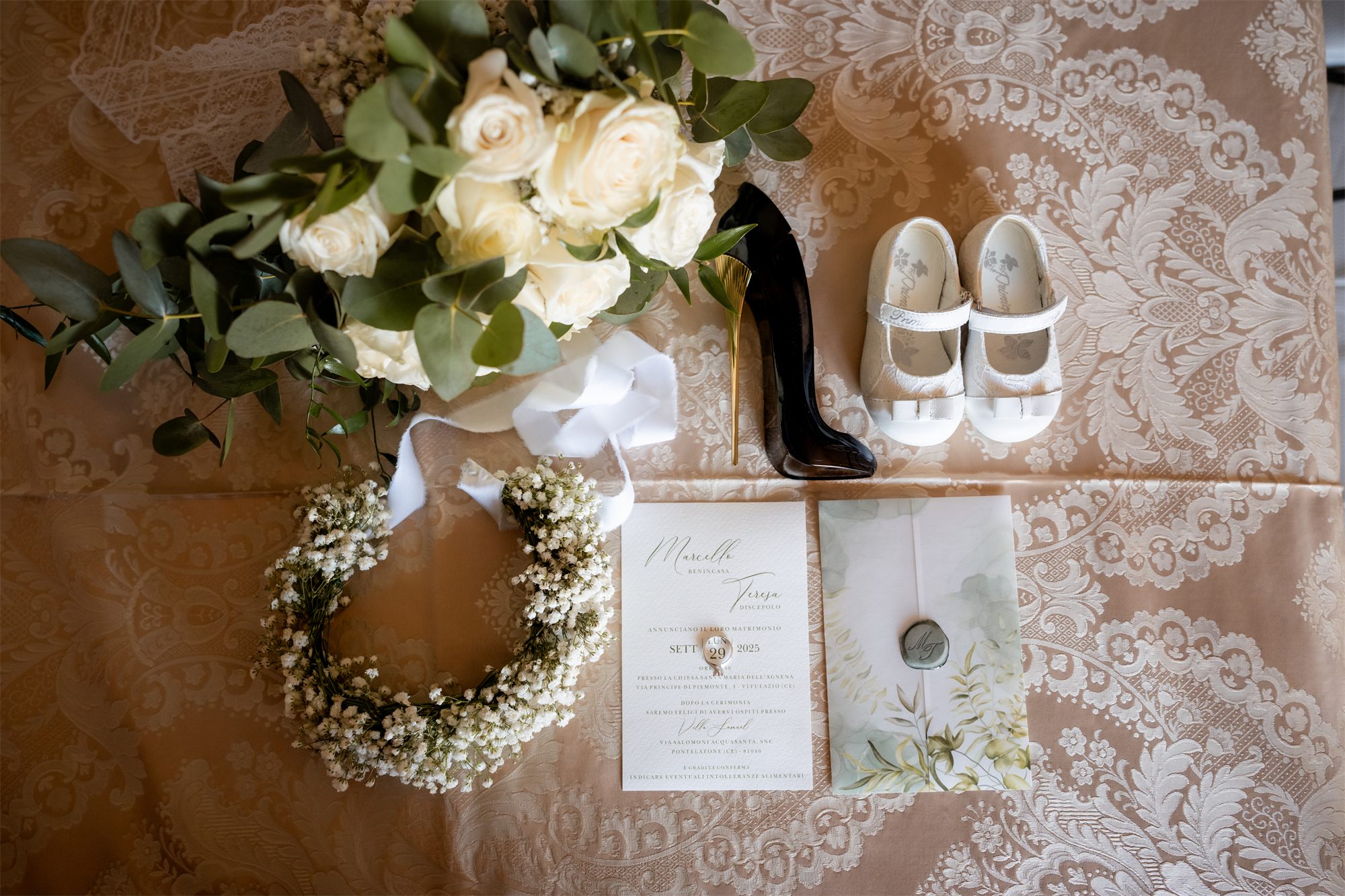 Scarpe, bouquet, coroncina e partecipazione su un tessuto damascato
