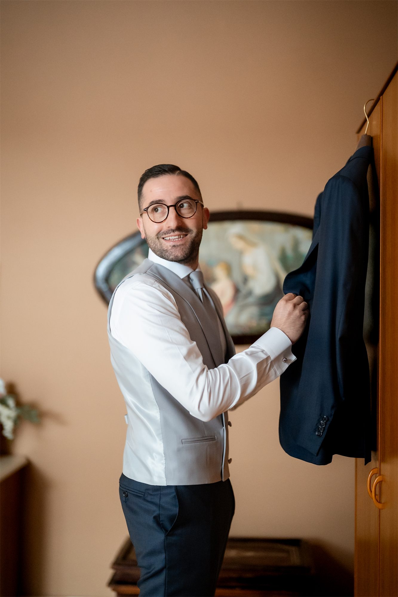 Marcello sorride mentre prende la giacca dall'armadio