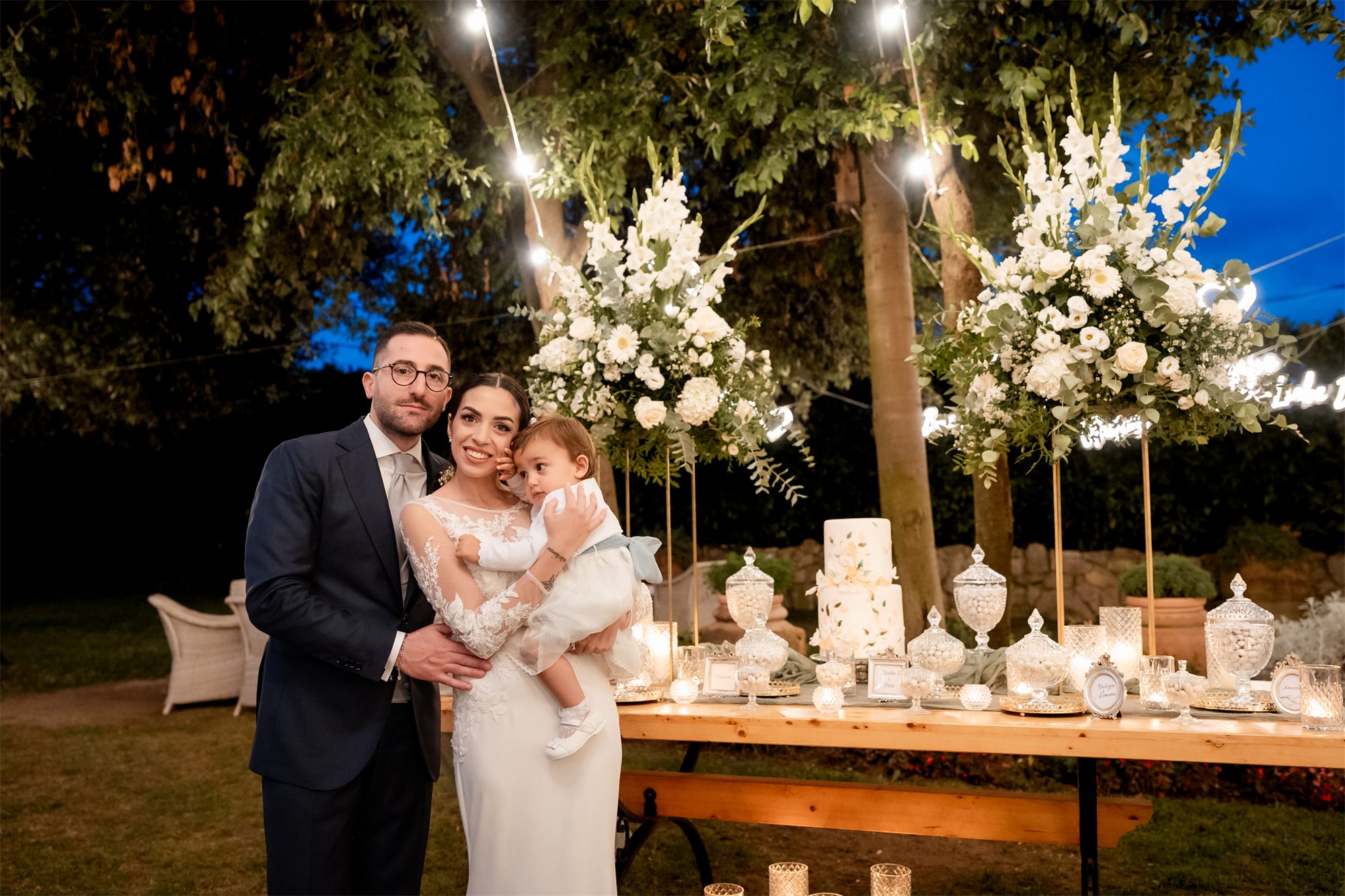 Marcello e Teresa con la bambina davanti ai fiori e alla confettata