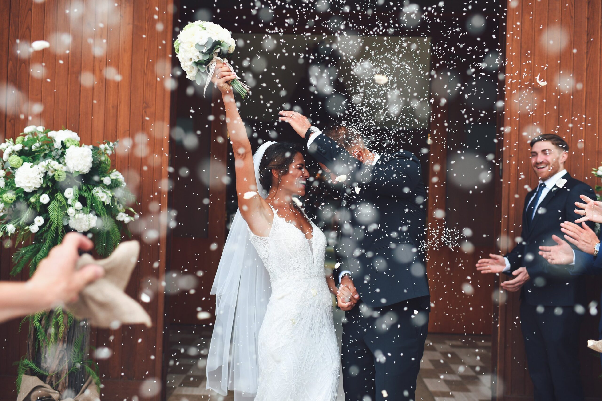Gli sposi escono dalla chiesa sotto il lancio del riso, con la sposa che alza il bouquet
