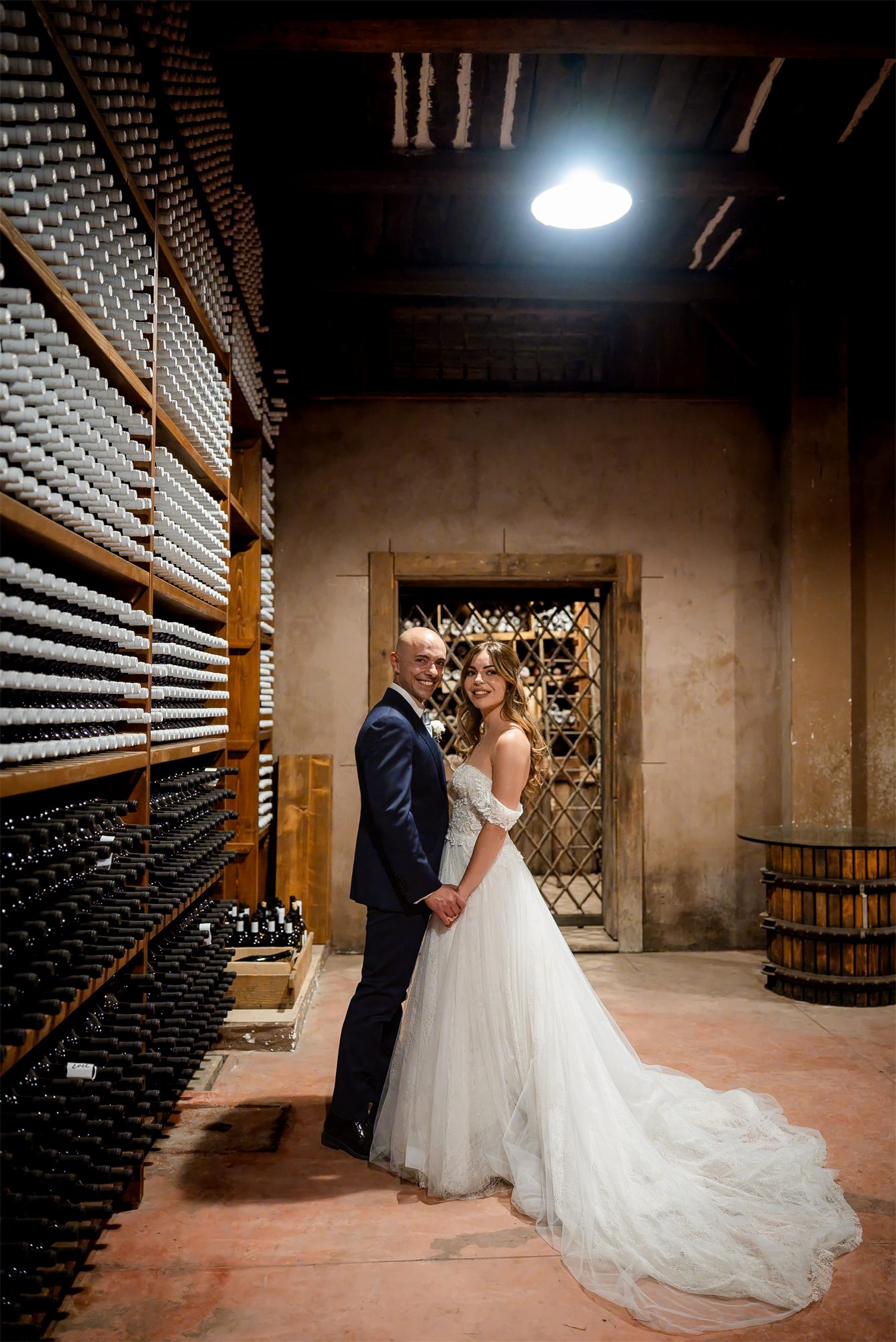 Alessia con l'abito da sposa tra le bottiglie di vino della cantina di Tenuta Alois, Pontelatone (Caserta)