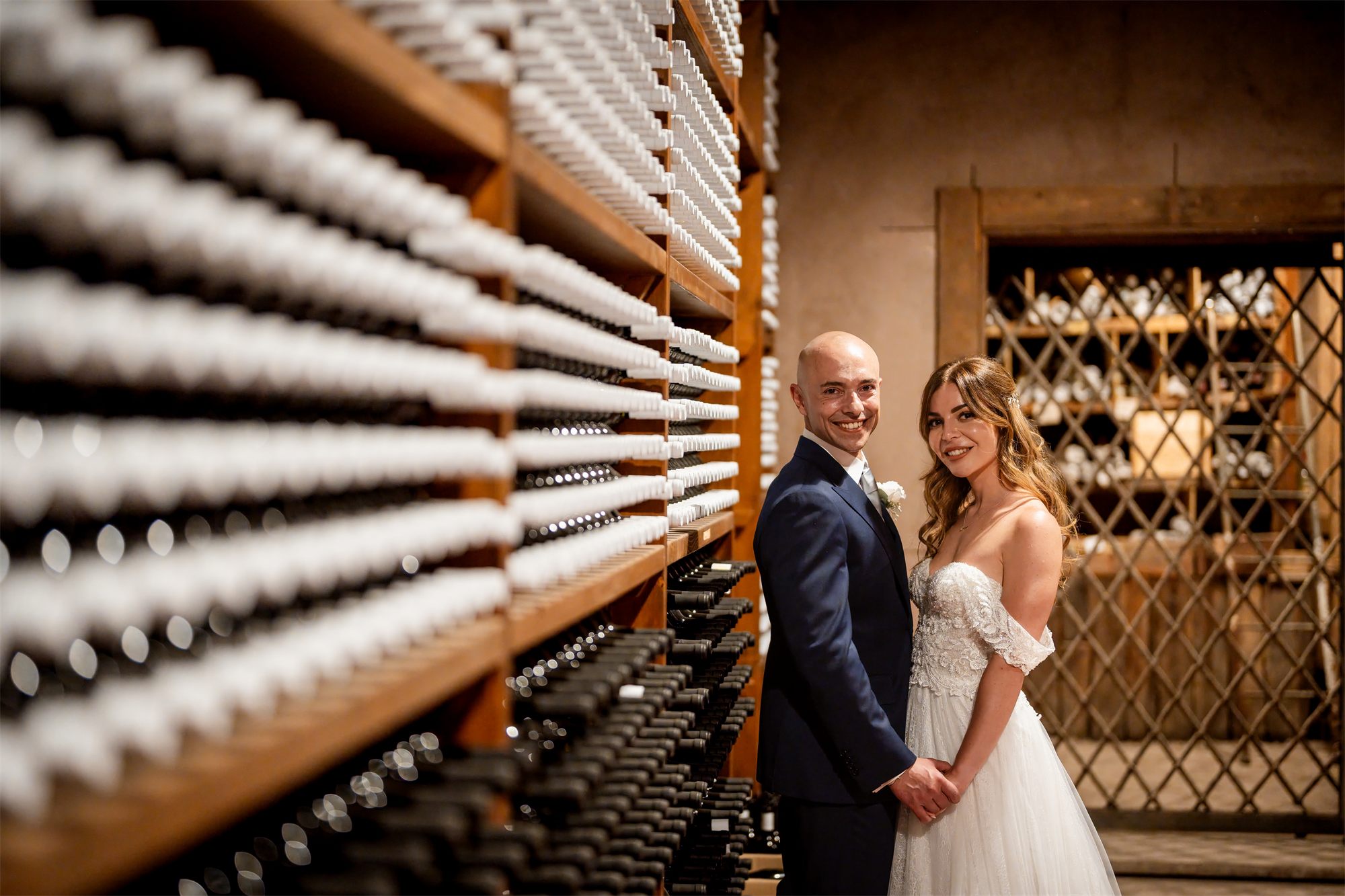 Stefano e Alessia abbracciati nella cantina di Tenuta Alois, Pontelatone (Caserta) tra le bottiglie