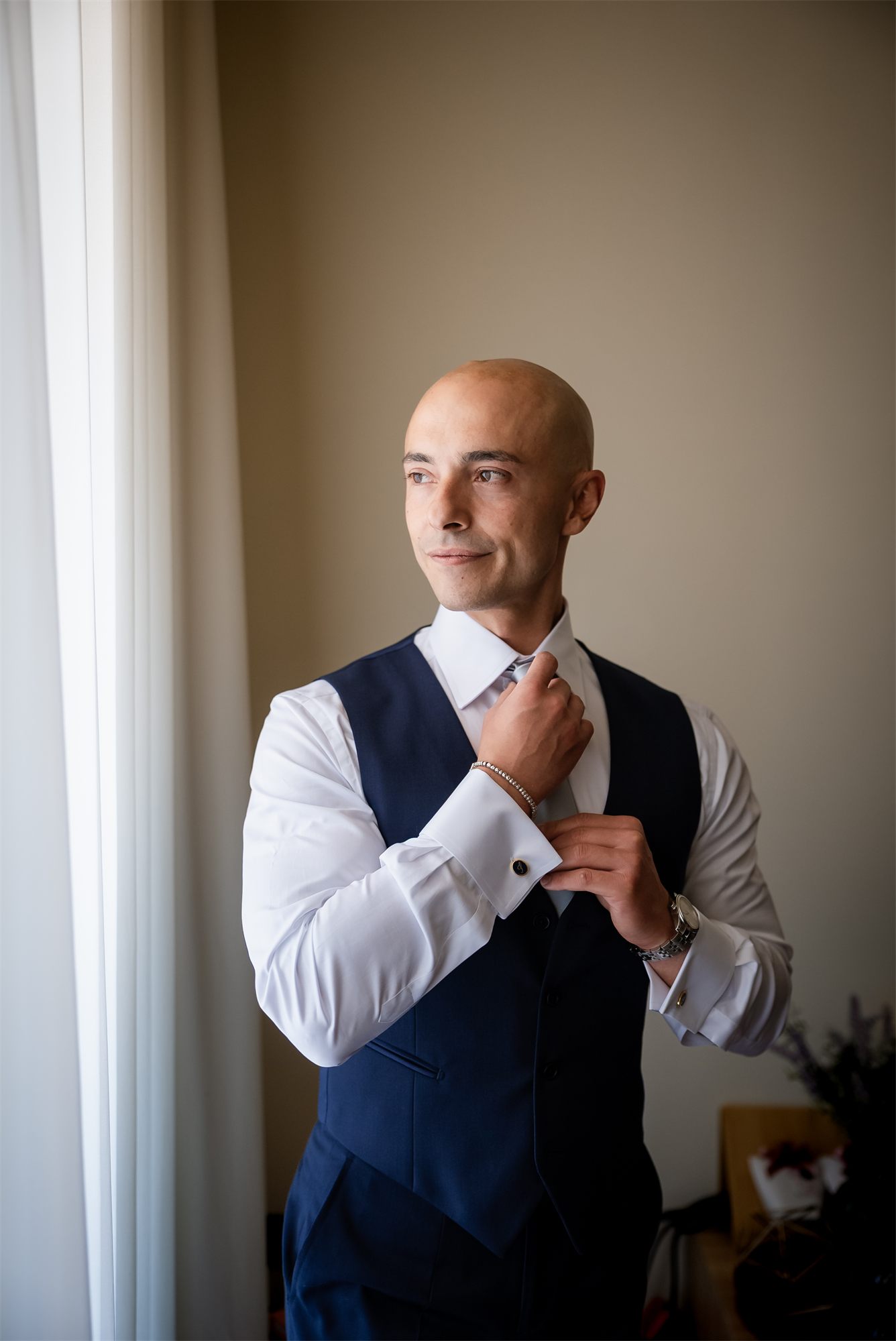 Lo sposo Stefano sistema il gilet blu davanti alla finestra
